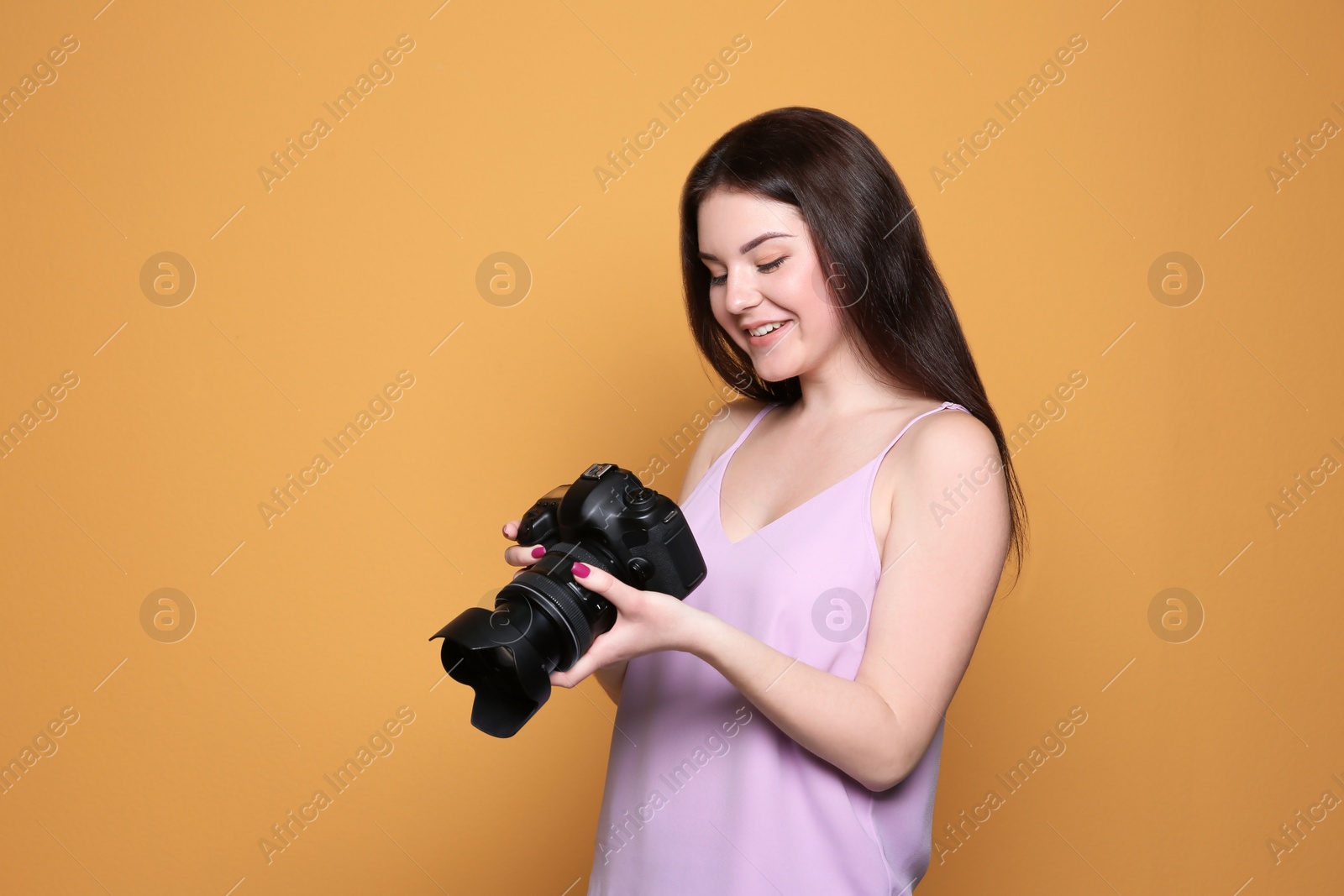 Photo of Female photographer with professional camera on color background