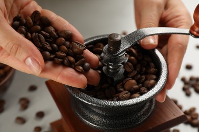 Photo of Woman using manual coffee grinder at table, closeup