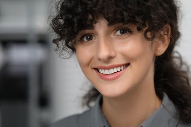 Photo of Portrait of confident businesswoman on blurred background. Beautiful lady with curly hair smiling and looking into camera. Space for text