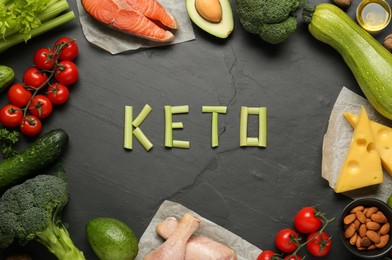 Photo of Word Keto Diet made of products surrounded by other food on black table, flat lay