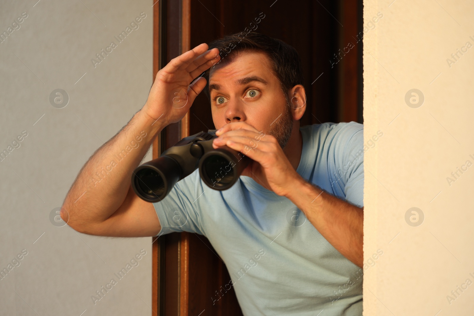Photo of Concept of private life. Curious man with binoculars spying on neighbours outdoors