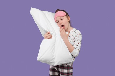 Girl with sleep mask and pillow yawning on purple background. Insomnia problem