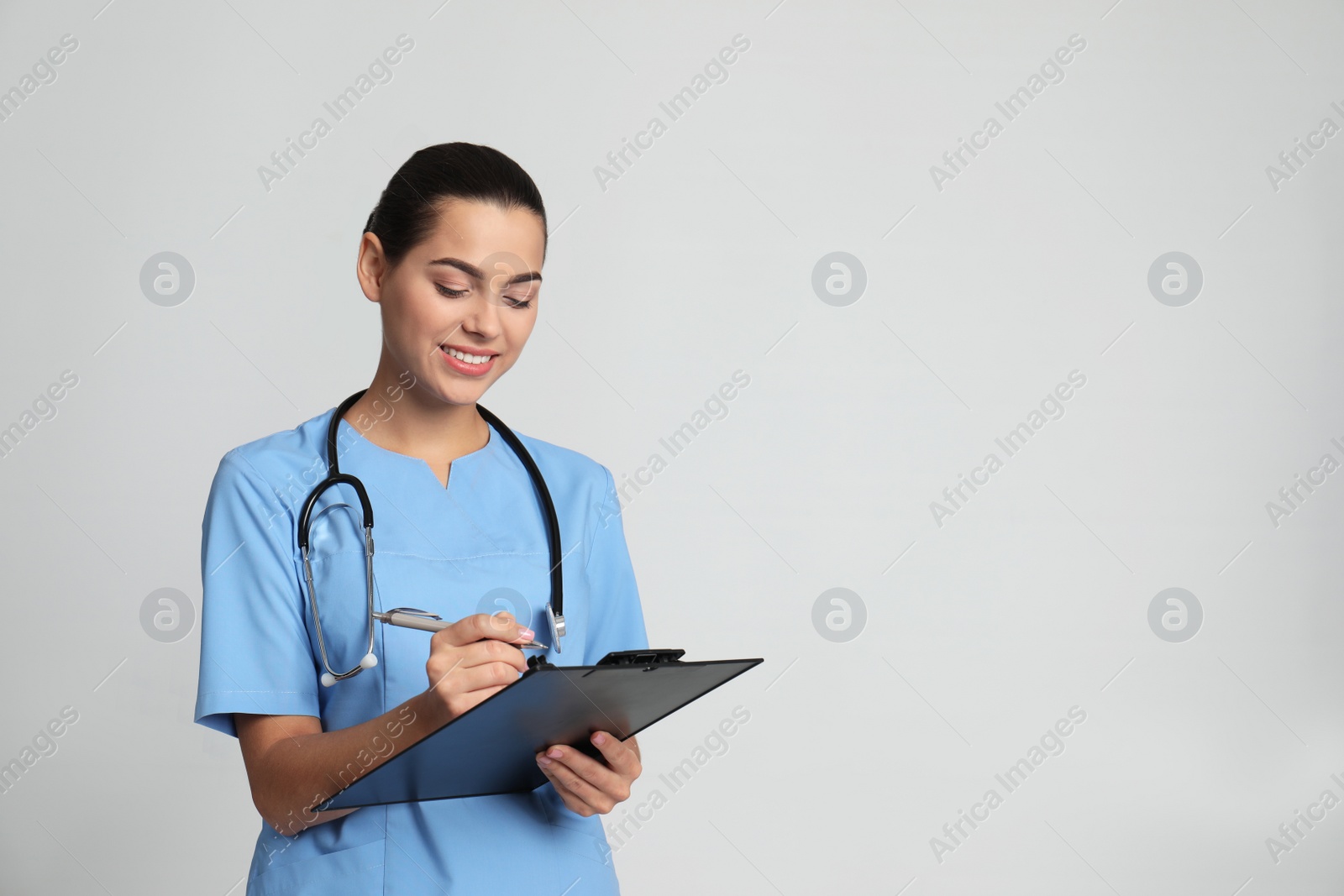 Photo of Portrait of young medical assistant with stethoscope and clipboard on color background. Space for text