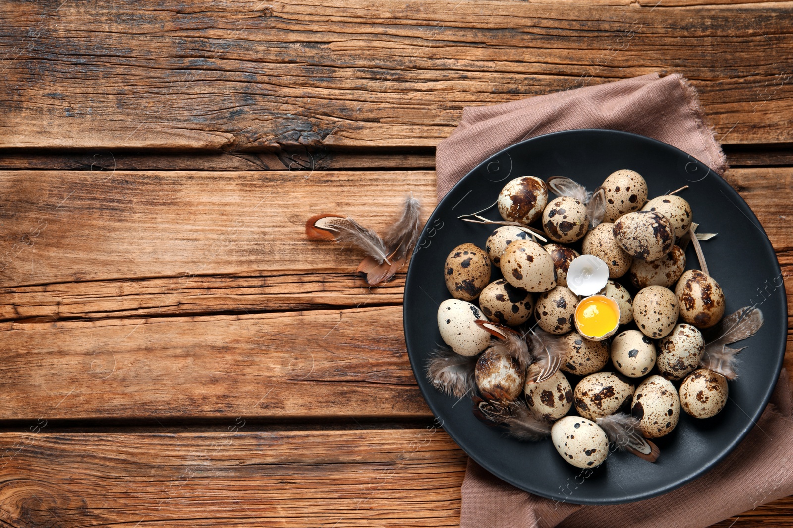 Photo of Plate with quail eggs on wooden table, top view. Space for text