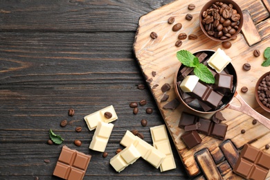 Photo of Flat lay composition with different kinds of chocolate on wooden table and space for text