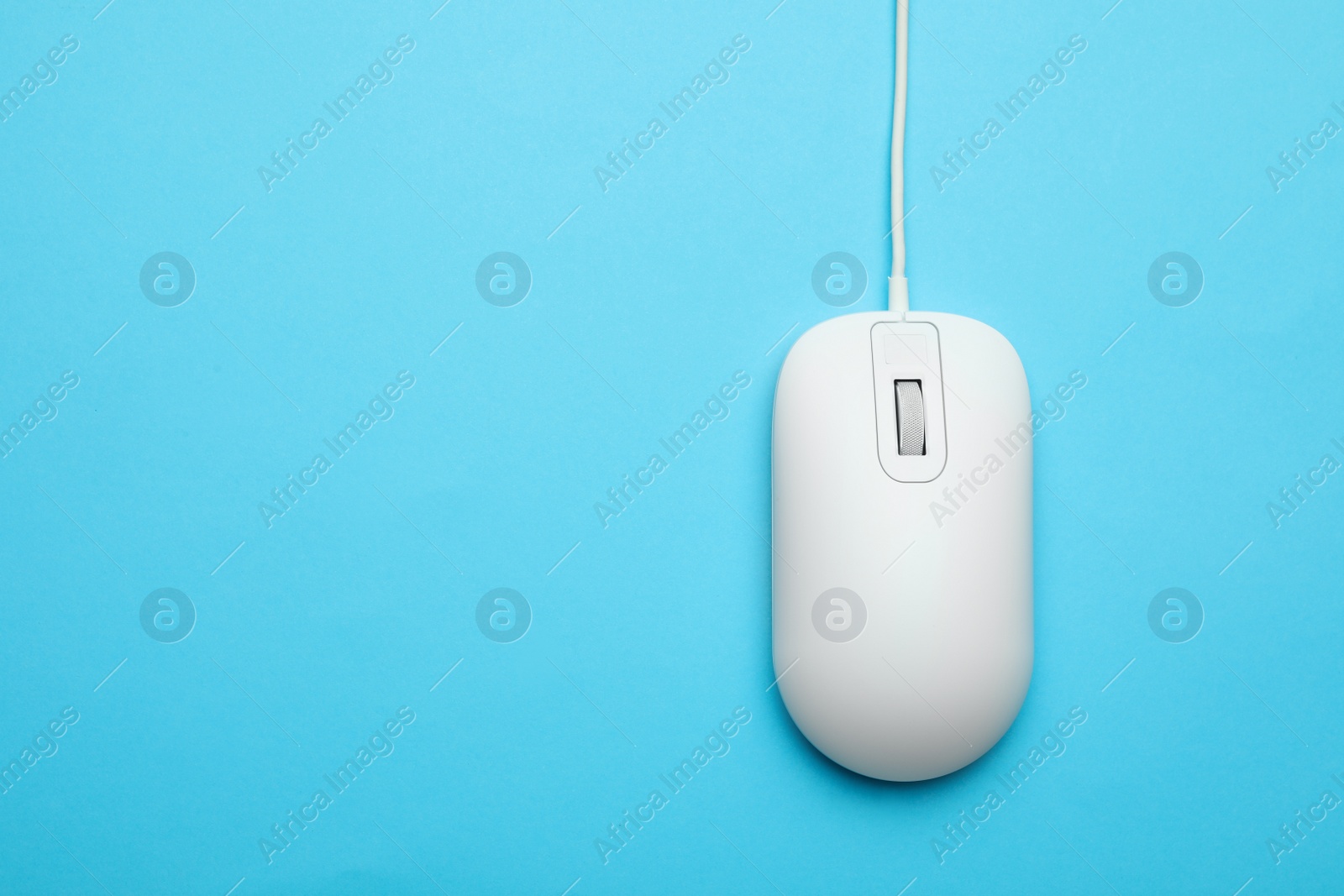 Photo of Wired computer mouse on light blue background, top view. Space for text