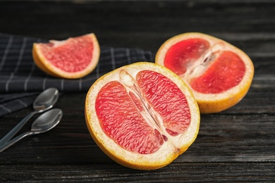 Photo of Fresh tasty grapefruits on dark table, closeup