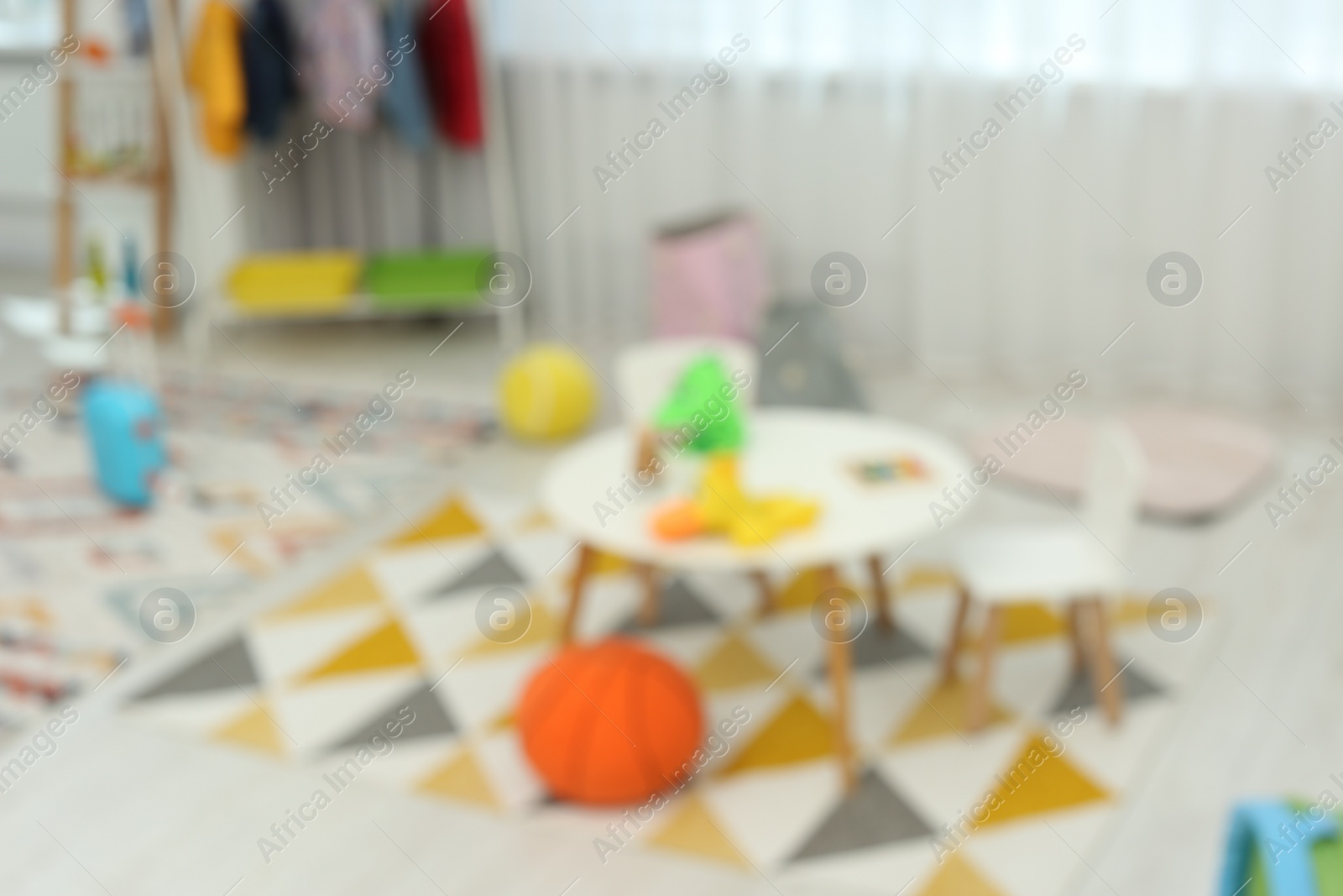 Photo of Blurred view of child`s playroom with different toys and furniture. Stylish kindergarten interior