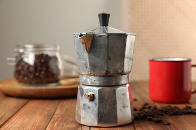 Photo of Moka pot and coffee beans on wooden table indoors, closeup