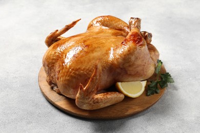 Tasty roasted chicken with parsley and lemon on light grey table