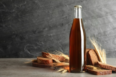 Bottle of delicious fresh kvass, spikelets and bread on grey table. Space for text