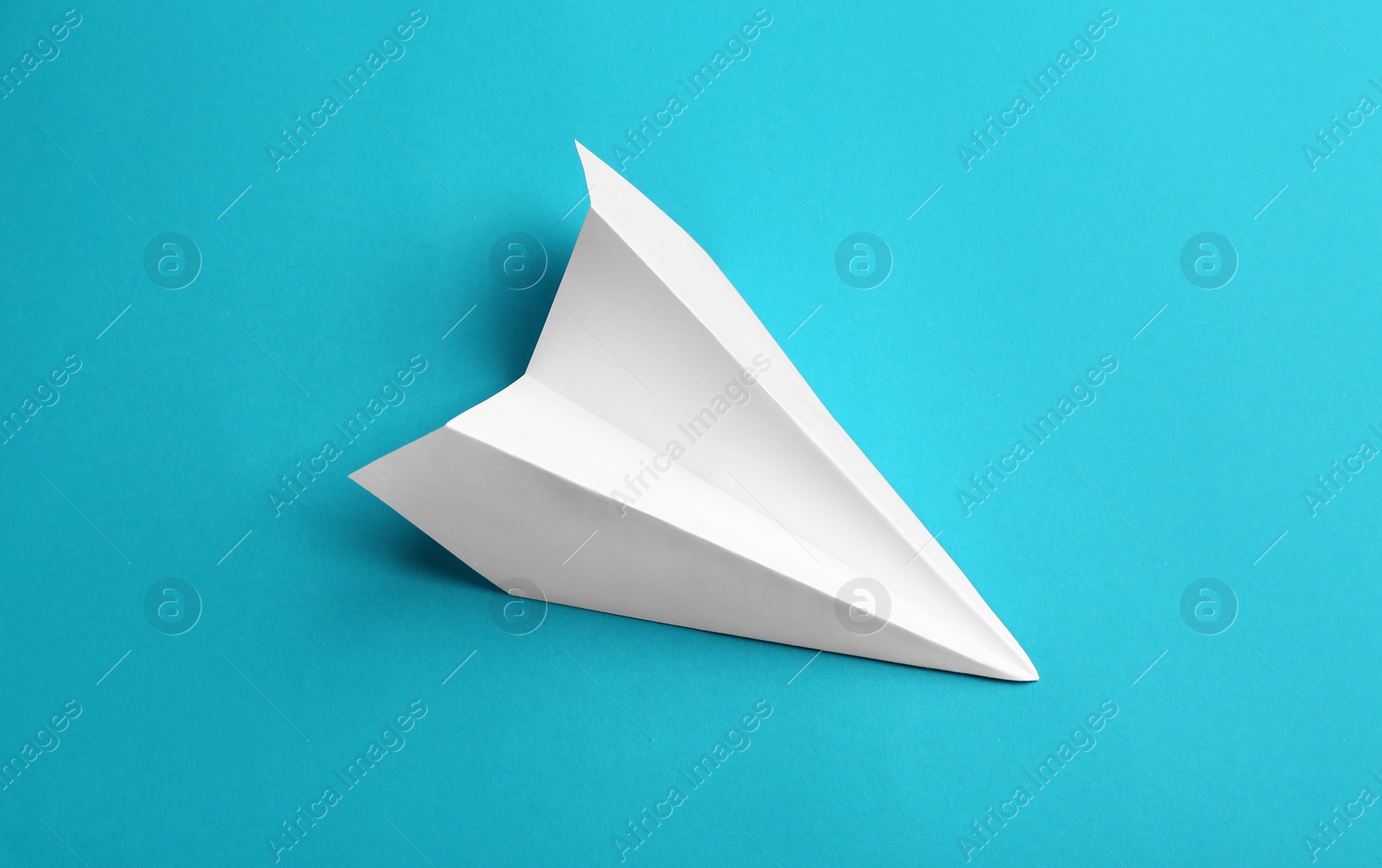 Photo of White paper plane on light blue background