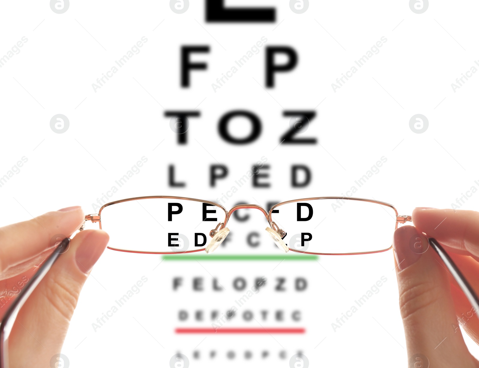 Image of Woman holding glasses, closeup. View through lenses on eye chart, white background