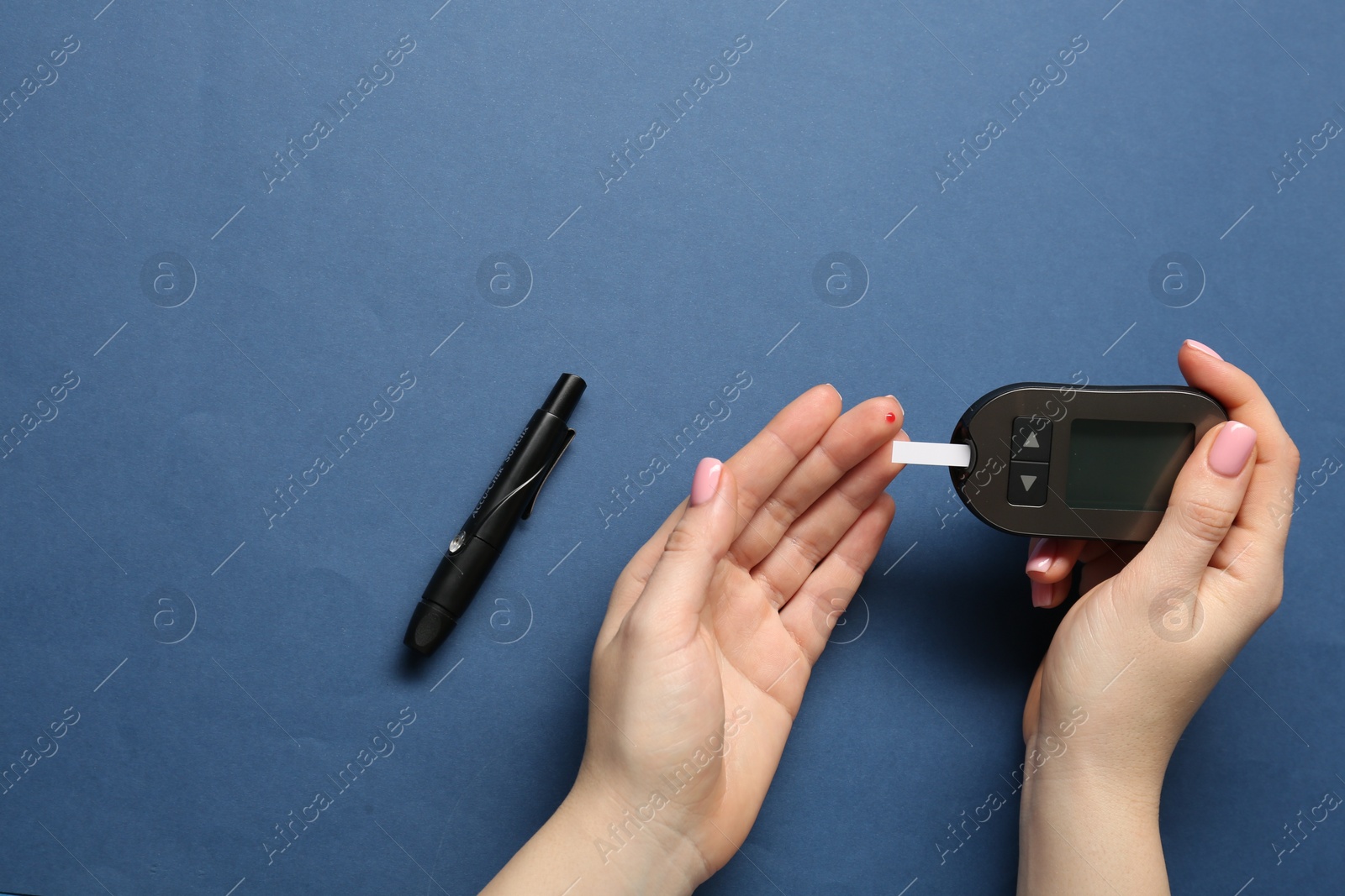 Photo of Diabetes. Woman checking blood sugar level with glucometer on blue background, top view. Space for text