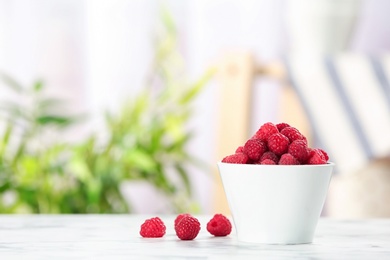 Photo of Bowl with ripe aromatic raspberries on table