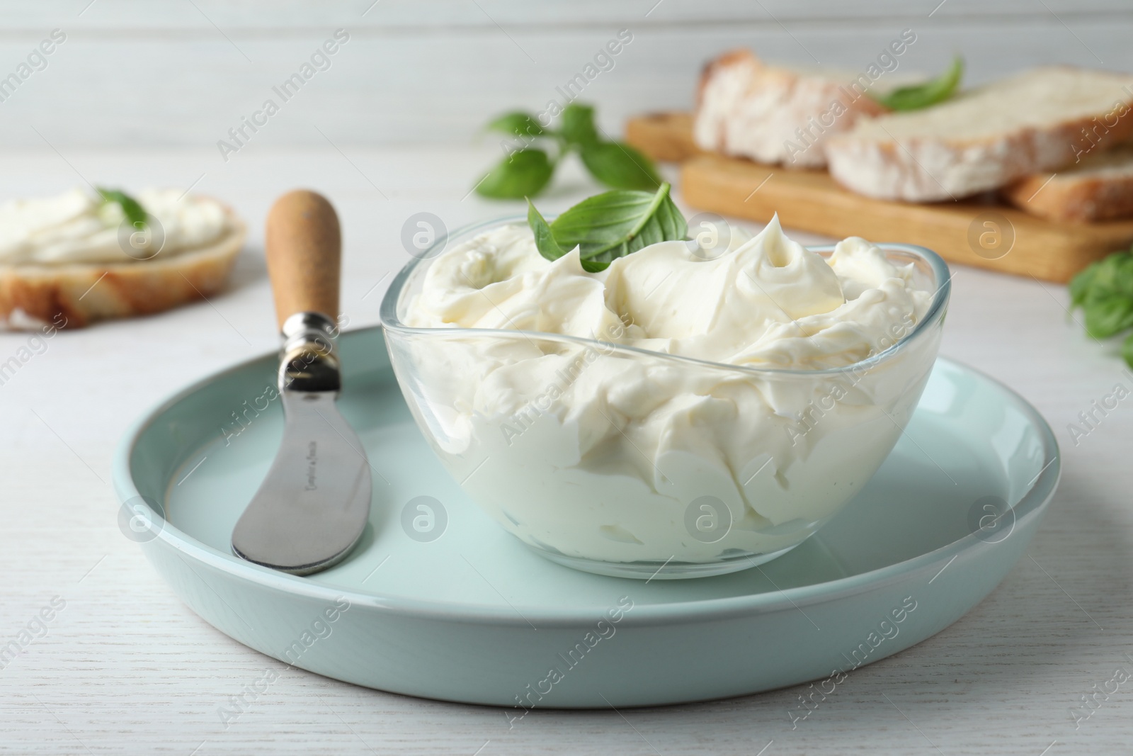 Photo of Tasty cream cheese with basil and knife on white wooden table