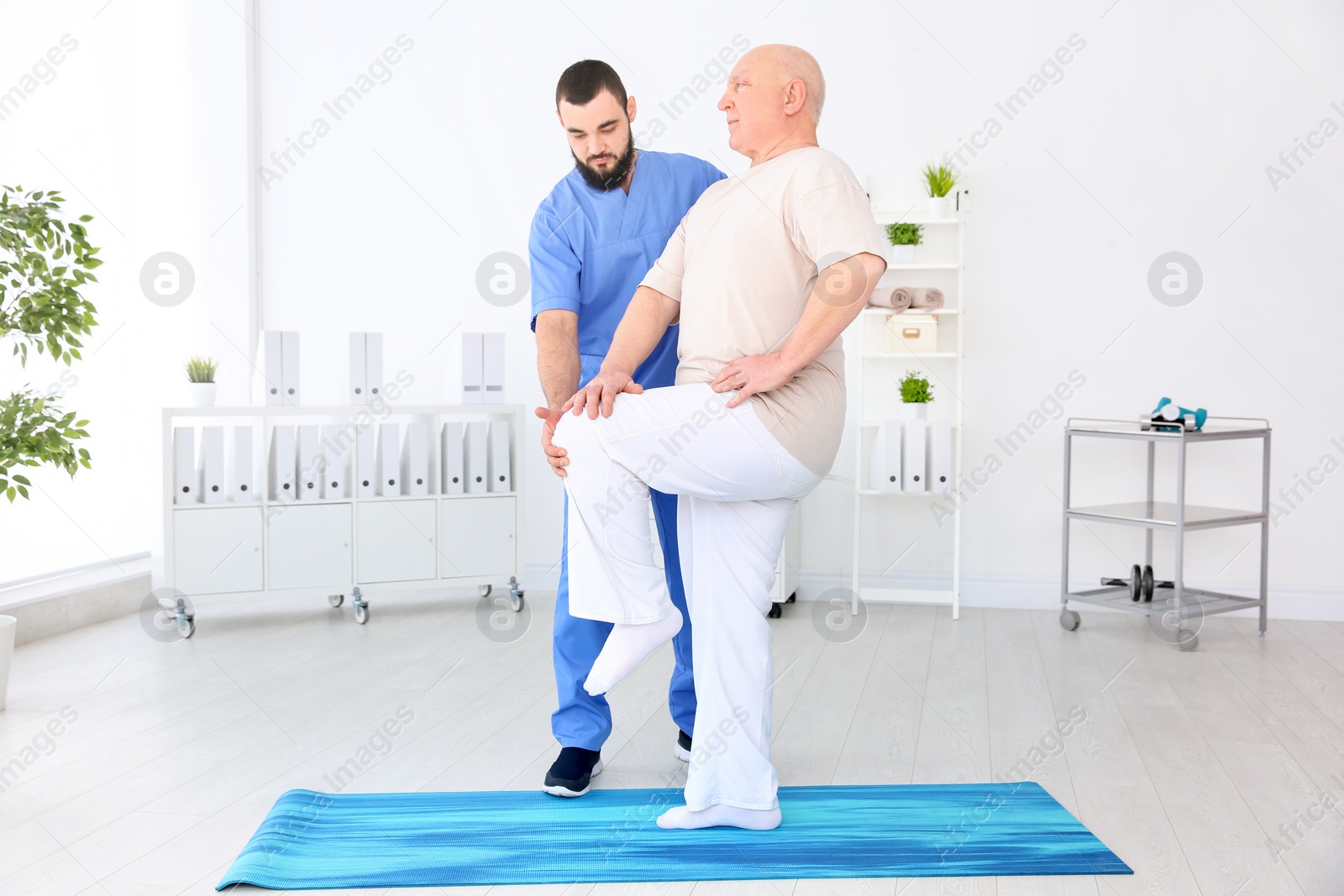 Photo of Young physiotherapist working with senior patient in clinic