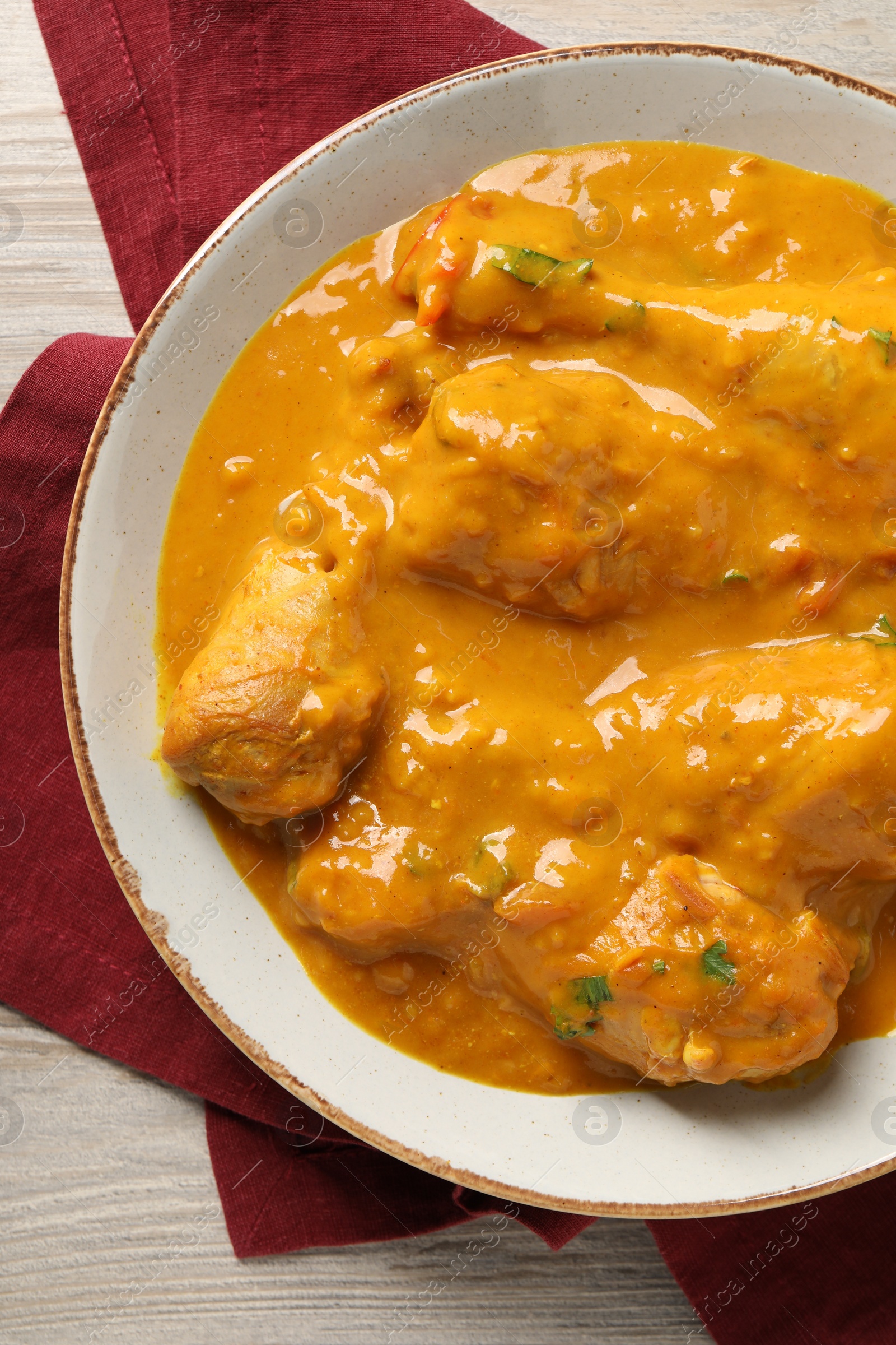 Photo of Tasty chicken curry on wooden table, top view