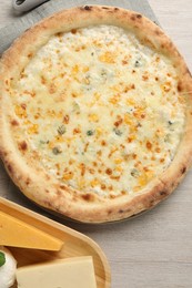 Delicious cheese pizza and different kinds of cheese on wooden table, flat lay