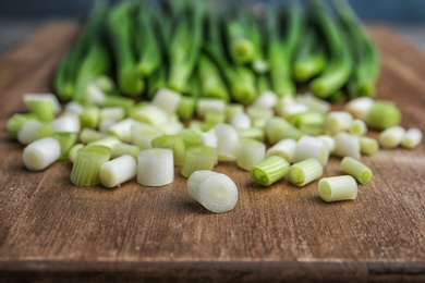 Photo of Chopped green onion on wooden board, closeup