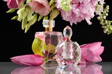 Luxury perfumes and floral decor on mirror surface against black background