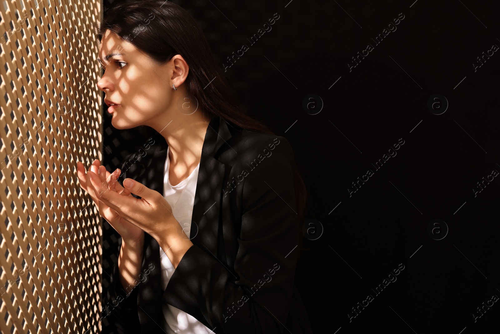 Photo of Woman talking to priest during confession near wooden partition in booth, space for text