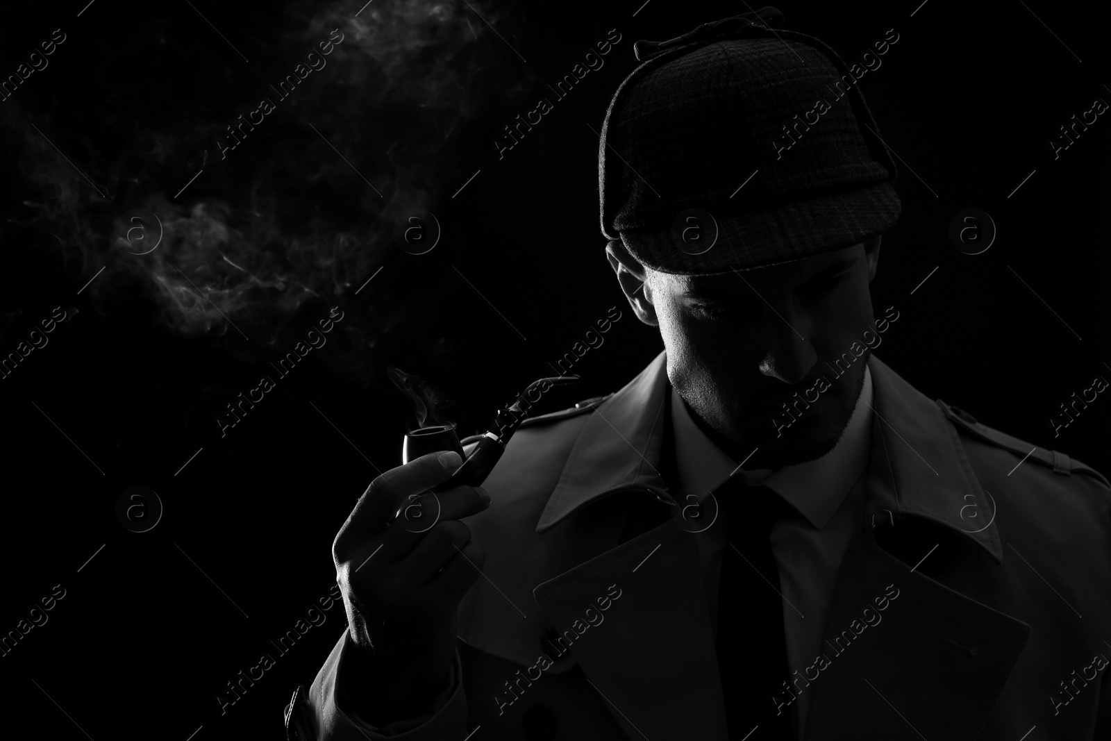 Photo of Old fashioned detective smoking pipe on dark background, black and white effect