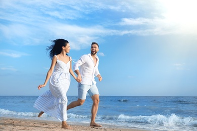 Happy young couple running together on beach