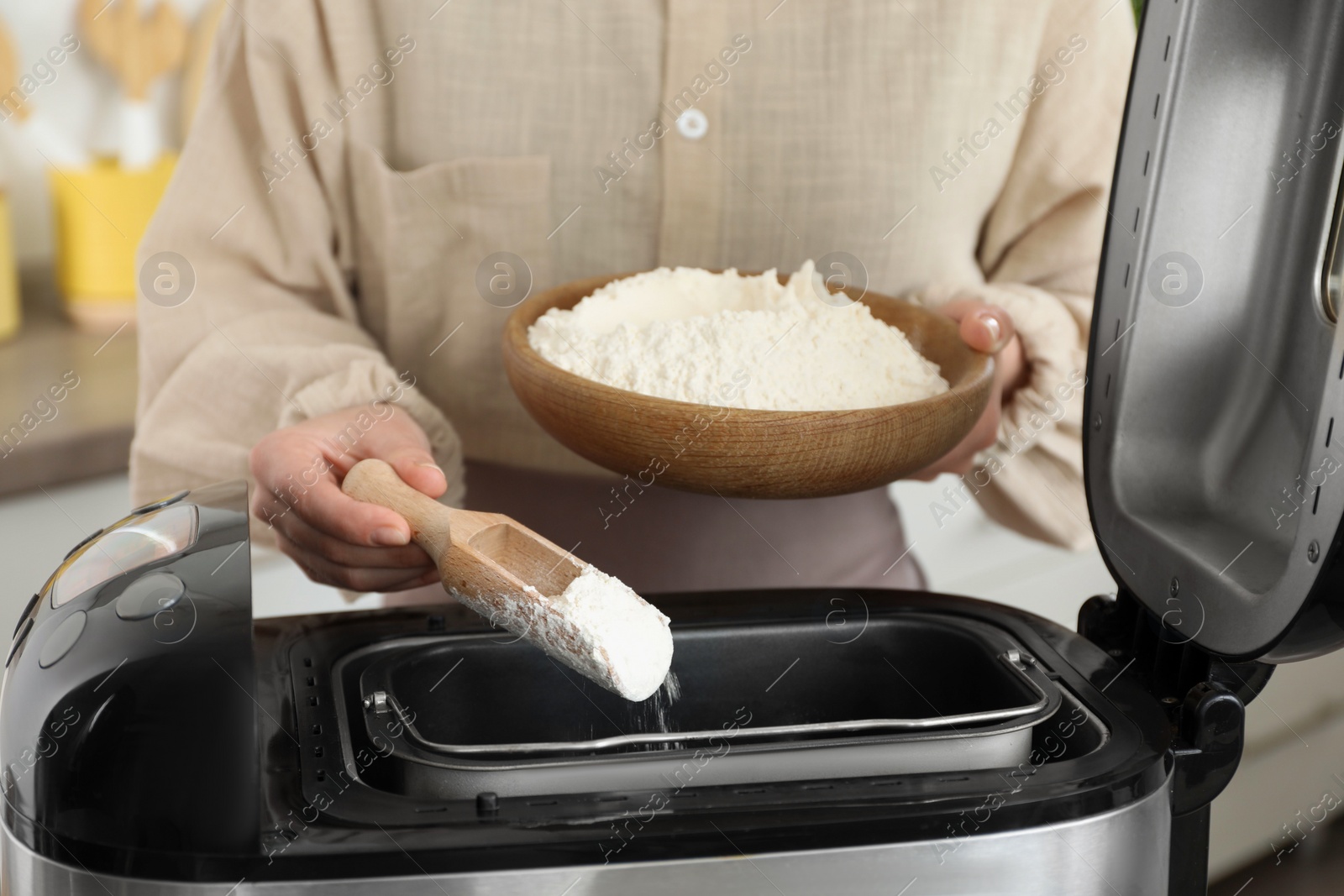 Photo of Making dough. Woman adding flour into breadmaker machine, closeup