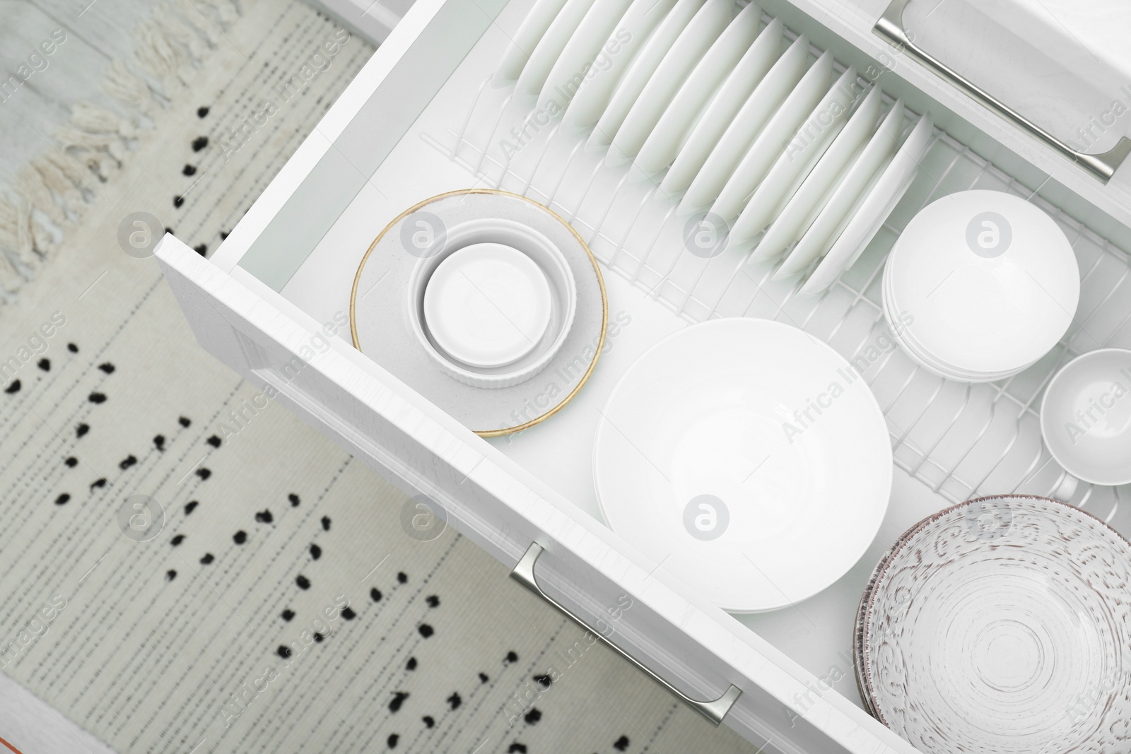 Photo of Open drawer with different plates and bowls in kitchen, above view