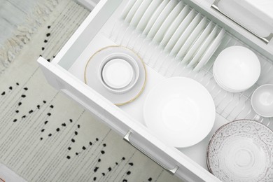 Open drawer with different plates and bowls in kitchen, above view
