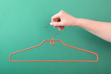 Woman holding hanger on green background, closeup