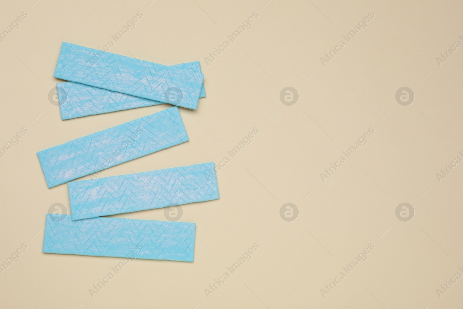 Photo of Sticks of tasty chewing gum on beige background, flat lay. Space for text