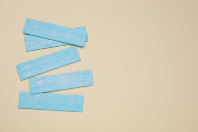 Photo of Sticks of tasty chewing gum on beige background, flat lay. Space for text