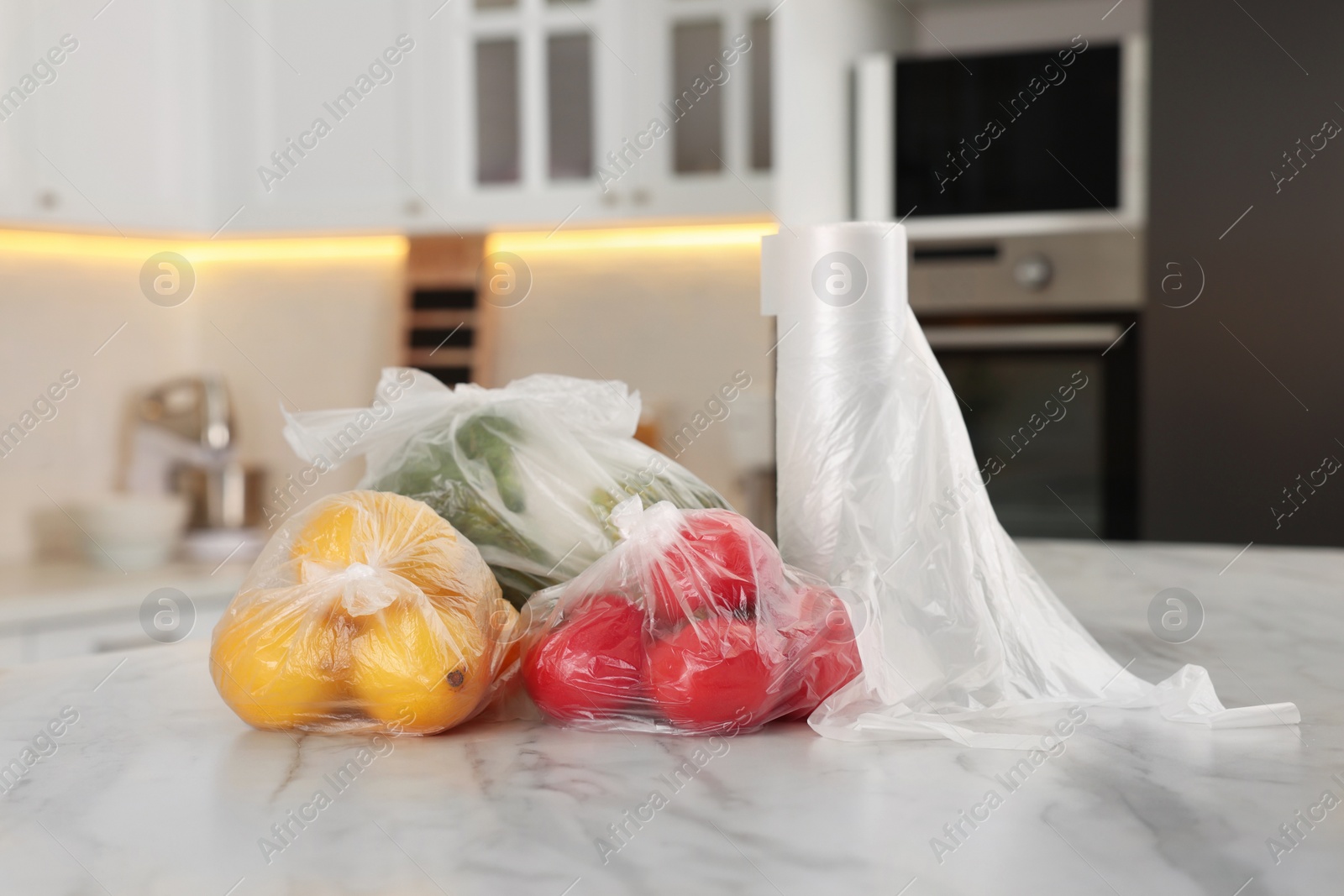 Photo of Plastic bags with different fresh products on white marble table in kitchen