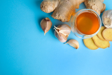 Photo of Fresh garlic and other natural cold remedies on light blue background, flat lay. Space for text