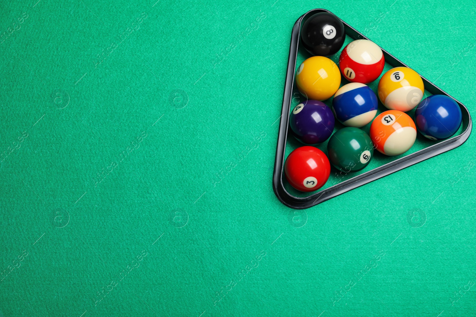 Photo of Plastic rack with billiard balls on green table, top view. Space for text