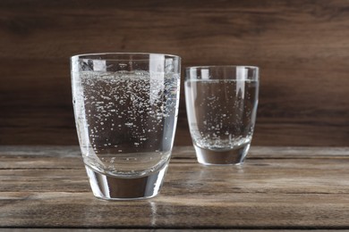 Photo of Glasses of soda water on wooden table. Space for text