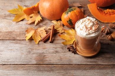 Photo of Glass cup with tasty pumpkin spice latte on wooden table