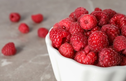 Photo of Bowl with ripe aromatic raspberries on table