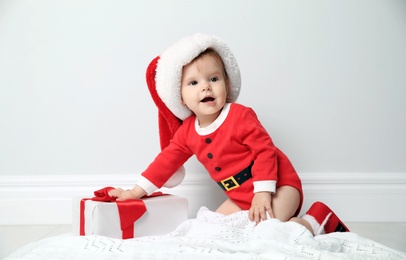 Cute little baby in Christmas costume with gift at home