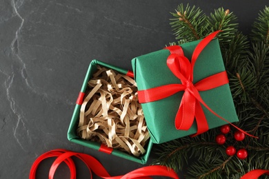 Green Christmas gift box with fir tree branches on grey table, flat lay