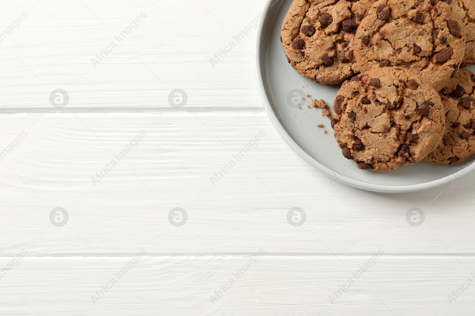 Photo of Delicious chocolate chip cookies on white wooden table, top view. Space for text