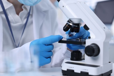 Scientist working with microscope in laboratory, closeup