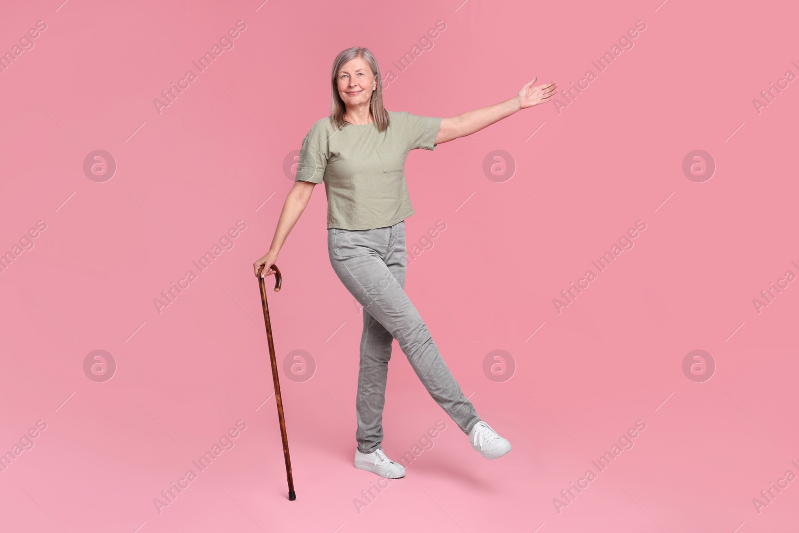 Photo of Senior woman with walking cane posing on pink background