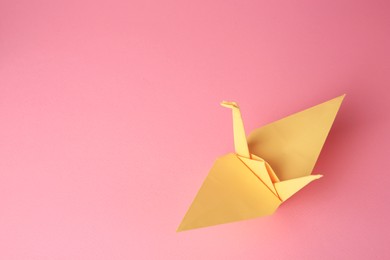 Photo of Origami art. Handmade paper crane on pink background, above view. Space for text