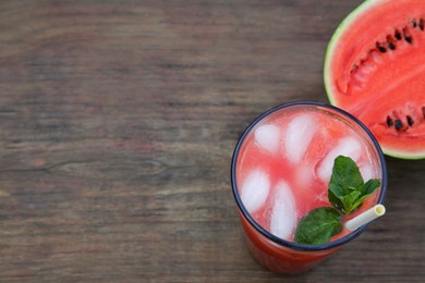 Photo of Glass of delicious watermelon drink with mint, ice cubes and fresh cut fruit on wooden table, top view. Space for text
