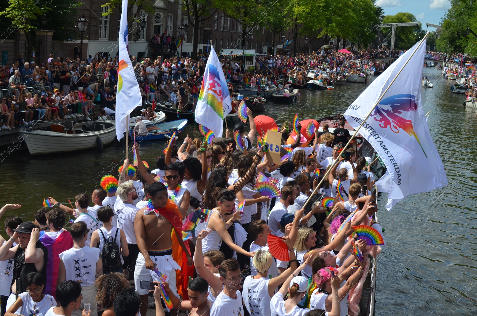 Photo of AMSTERDAM, NETHERLANDS - AUGUST 06, 2022: Many people in boats at LGBT pride parade on river