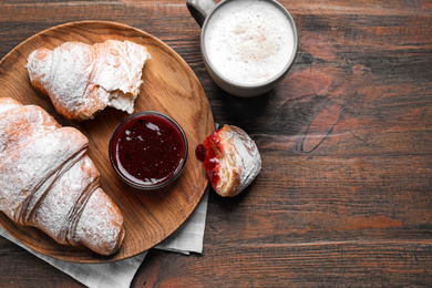 Photo of Fresh croissants with jam and coffee on wooden table, flat lay. Space for text