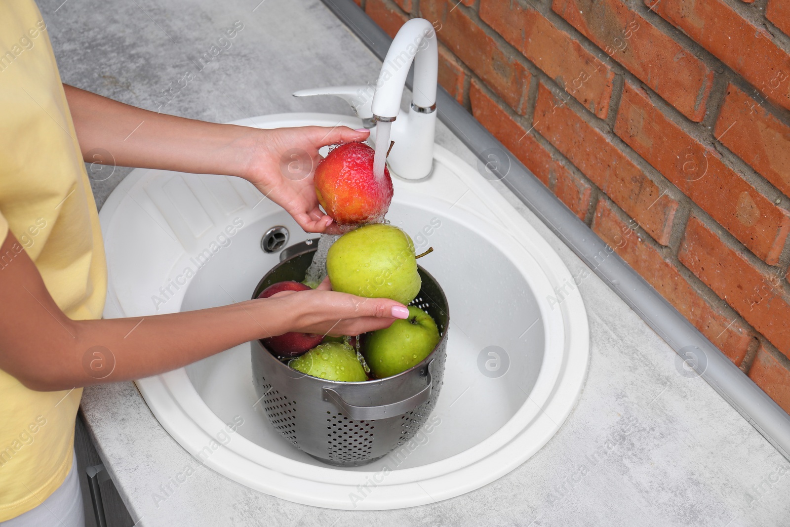 Photo of Woman washing fresh apples in kitchen sink, closeup